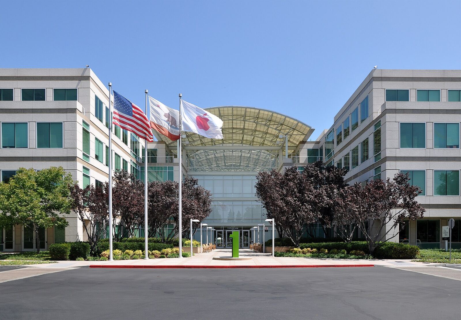 Apple headquarters in Cupertino, California displays flags on a sunny day.