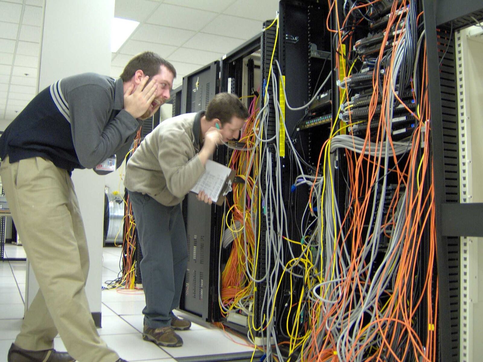 Data Center | Life of Internet Two technicians inspect a server rack filled with tangled network cables in a data center.